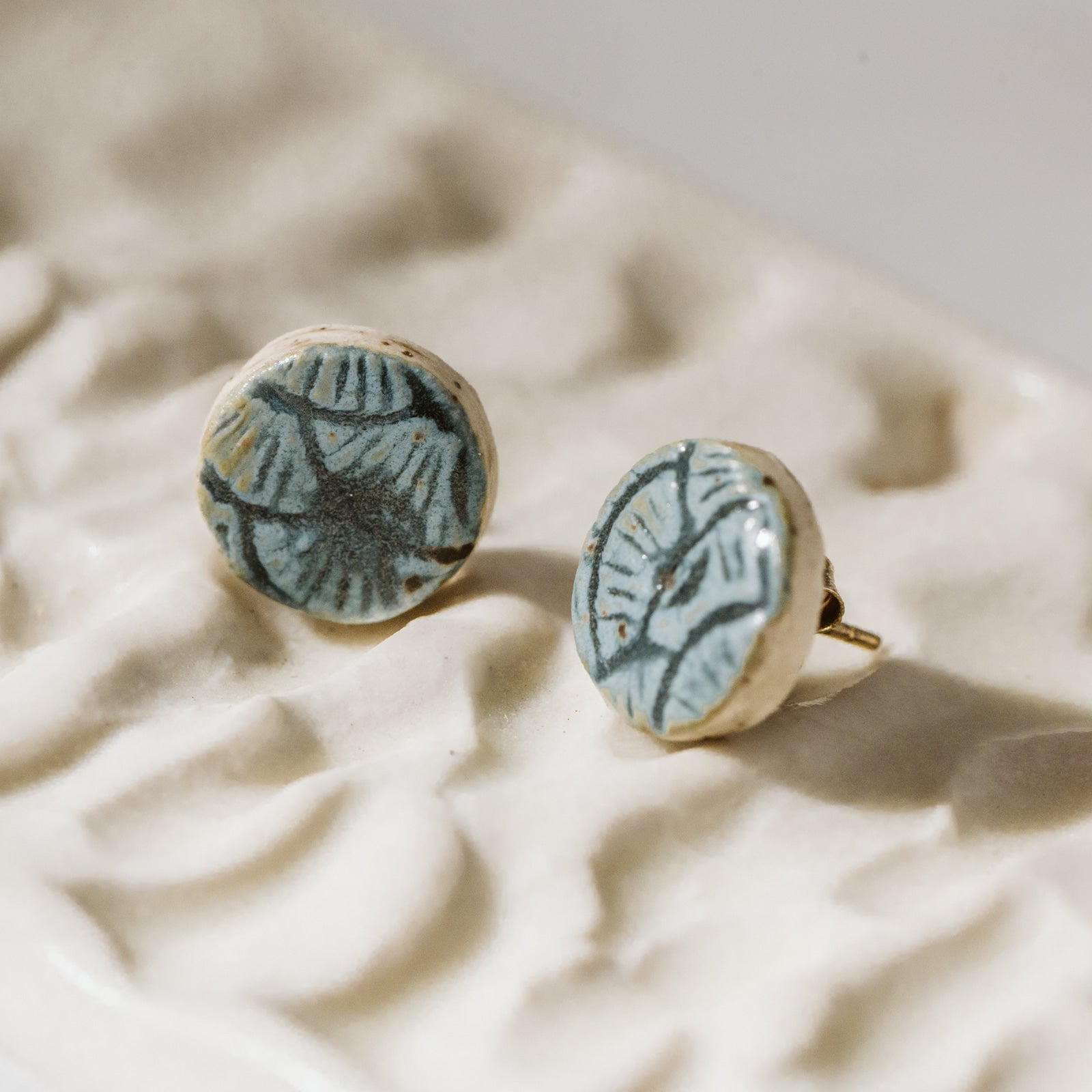 Boucles d'oreilles bleues en céramique, grès blanc. Étampées motifs géométriques. Créées par Coralie Huckel artiste céramiste en Estrie